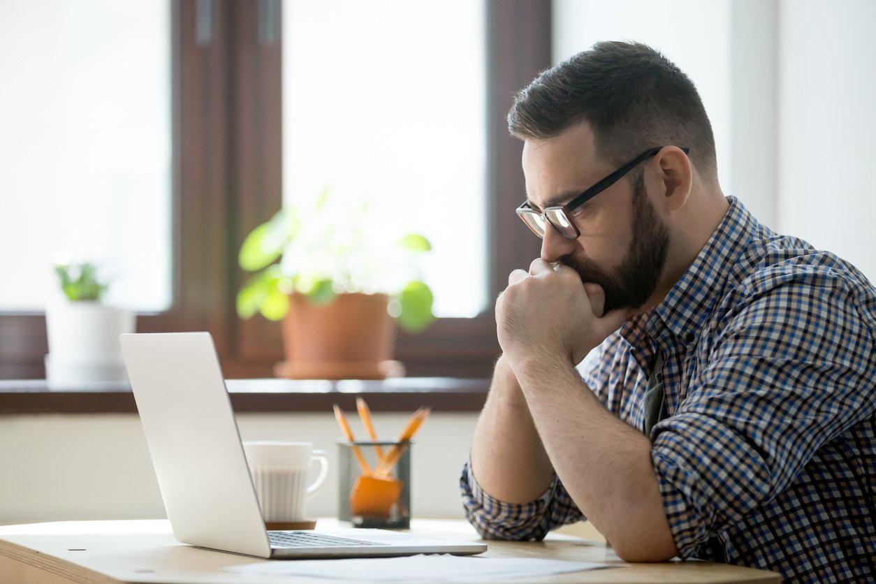 Man contemplatively looking at his laptop