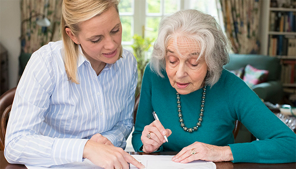 Woman helping an elder with paperwork