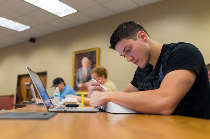 Student in classroom reviews textbook