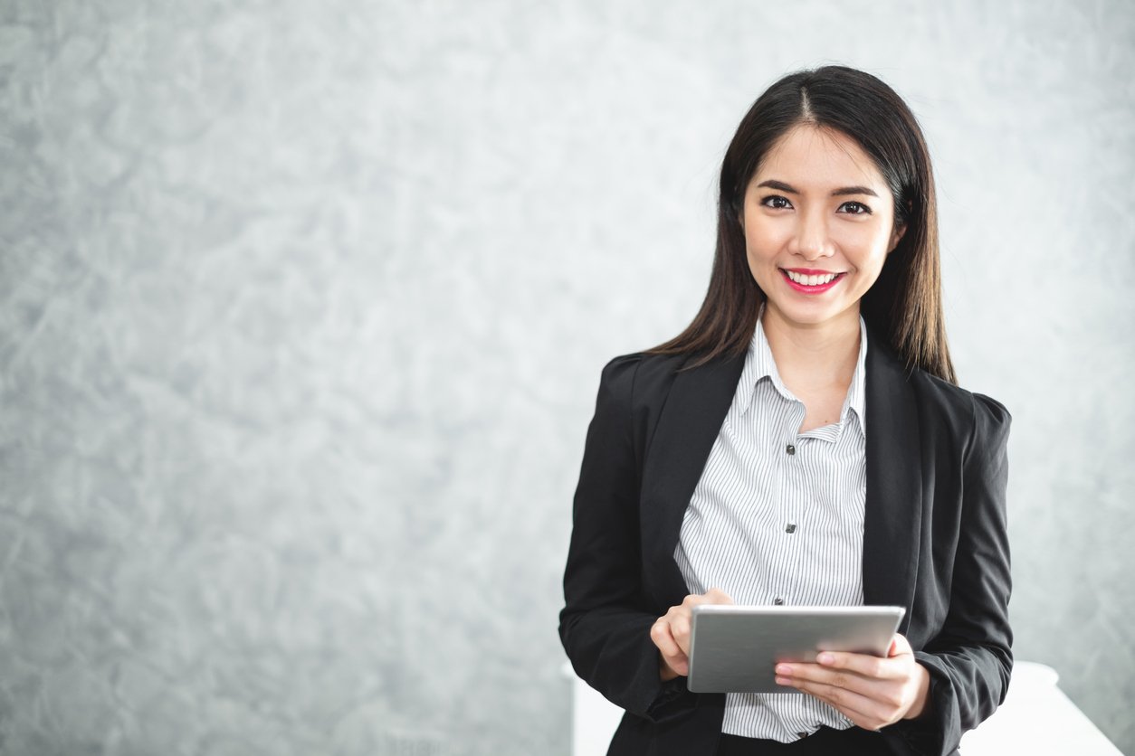 Young woman in business attire holding a tablet to take the LSAT